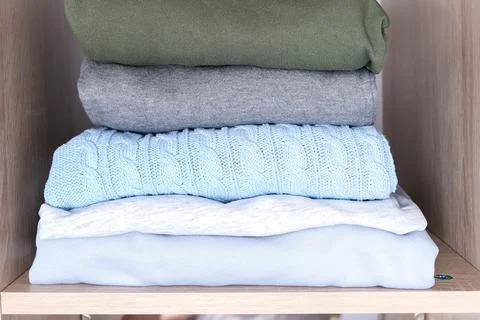 A stack of organized clothes on a shelf in a wardrobe Stock Photos
