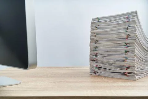 Stack of overload paperwork report and computer on wooden table Stock Photos