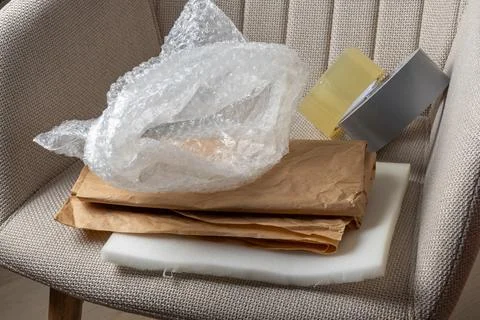 A stack of packing materials on a chair with bubble wrap and tape ready for.. Foto stock