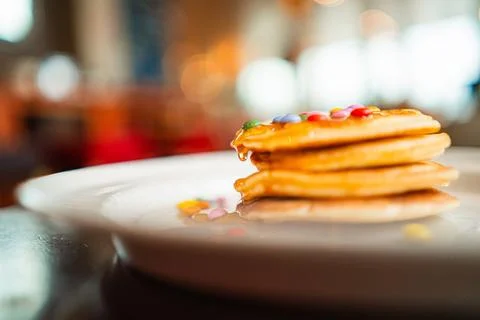 Stack of Pancakes with Bee Honey Dropping Down and Chocolate Lentils as Toppi Stock Photos