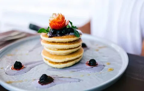 Stack of pancakes with berries and syrup on a white plate Stock Photos