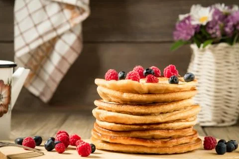 Stack of pancakes with berries on a wooden table in a rustic style Stock Photos