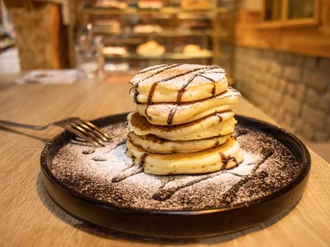 Stack of pancakes on a black plate on a table in a cafe Foto stock