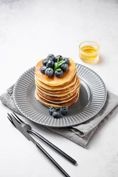 Stack of pancakes with blueberries and suryp on a gray plate on a light  ba.. Stock Photos
