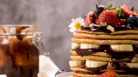 Stack of Pancakes with Chocolate Sauce, Bananas, and Fresh Berries Stock Photos