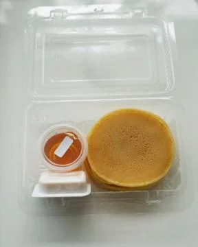 Stack of pancakes in a container transparent clear box with honey and butter  Foto stock