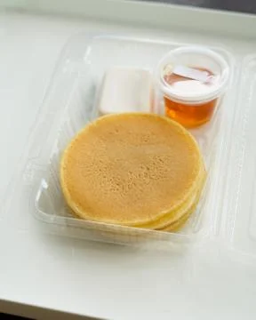 Stack of pancakes in a container transparent clear box with honey and butter  Foto stock