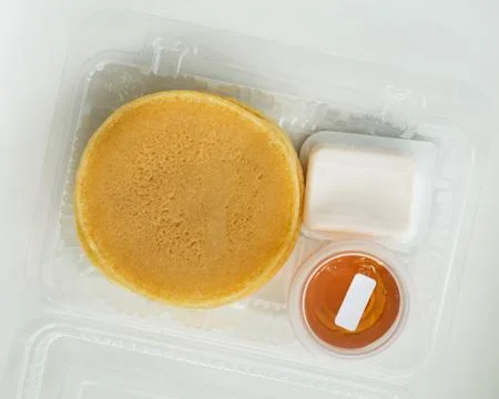 Stack of pancakes in a container transparent clear box with honey and butter  Foto stock