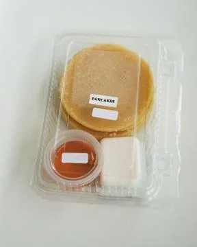 Stack of pancakes in a container transparent clear box with honey and butter  Foto stock