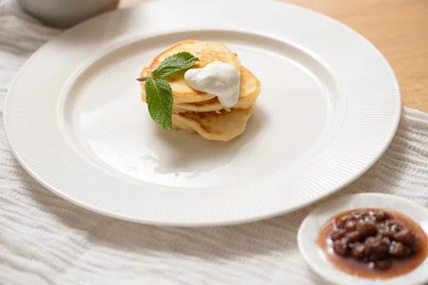 Stack of pancakes with cream and mint on white plate Stock Photos