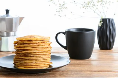 Stack of pancakes, dark mug and coffee pot on wooden table Side view Stock Photos