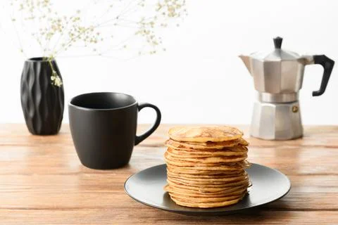 Stack of pancakes, dark mug and coffee pot on wooden table Stock Photos