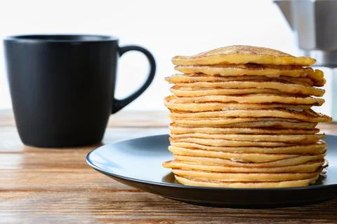 Stack of pancakes, dark mug and coffee pot on wooden table Close-up Stock Photos