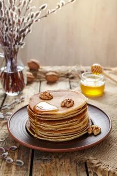 Stack of pancakes with flowing honey and nuts on table Stock Photos