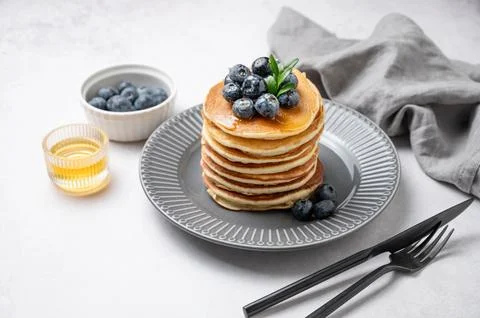 Stack of pancakes with fresh blueberries and suryp on a gray plate on a lig.. Stock Photos
