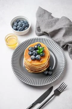 Stack of pancakes with fresh blueberries and suryp on a gray plate on a lig.. Stock Photos