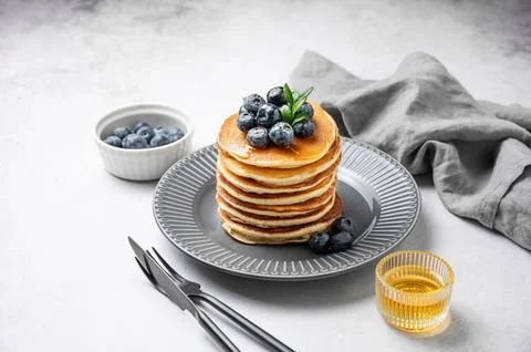 Stack of pancakes with fresh blueberries and suryp on a gray plate on a lig.. Stock Photos