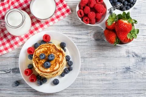 Stack of pancakes with fresh blueberry, raspberry and honey, milk and berries Stock Photos
