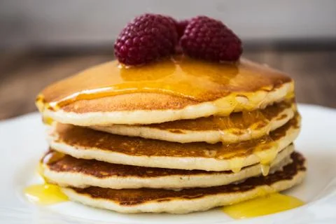 Stack of pancakes with honey and raspberry on white plate Stock Photos