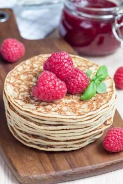Stack of pancakes or fritters with raspberry on wooden board, raspberry jam o Fotos de archivo