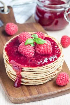 Stack of pancakes or fritters with raspberry jam and berries on a wooden boar 스톡 사진