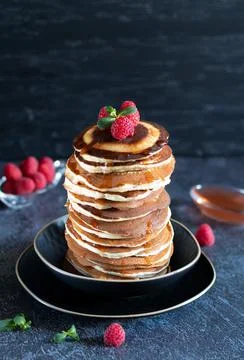 Stack of pancakes with raspberrie and maple syrup on black background Stock Photos