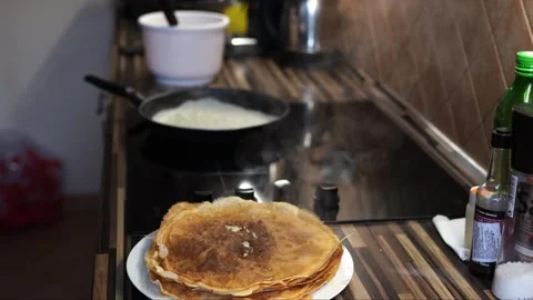 Stack of pancakes is steaming on a plate on the table next to a frying pan on Stock-Footage 284500519