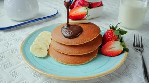 Stack of pancakes with strawberries and syrup on blue plate Stock Photos