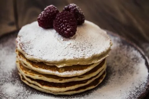 Stack of pancakes with sugar powder and raspberry Stock Photos