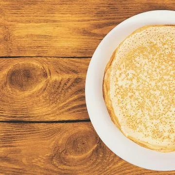 A stack of pancakes on a white plate on a wooden table. Place for the label,  Stock Photos