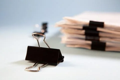 A stack of paper clips and a clip on a black background. Stock Photos