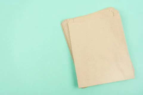 Stack of paper craft bags on mint background with copy space. Stock Photos