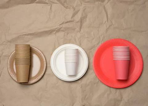 Stack of paper cups and round plates on a brown paper background Stock-Fotos
