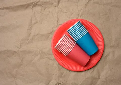 Stack of paper cups and round plates on a brown paper background Foto stock