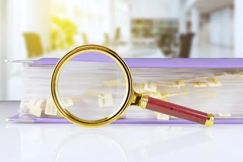 Stack of paper documents in a purple folder with bookmarks and a magnifying g Stock Photos