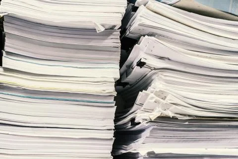 The stack of paper lay on a messy table in the office in the storage room. Stock Photos