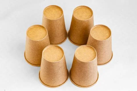 Stack of paper mugs. Six disposable paper cups made of cardboard kraft paper. Stock Photos