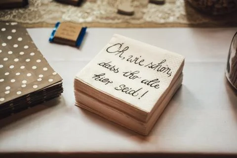 Stack of paper napkins laying on serving table. Translation: "How nice, that you Stock Photos