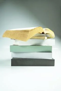 A stack of paperback books with an open book, showcasing empty pages agains.. Stock Photos