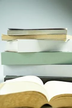 A stack of paperback books with an open book, showcasing empty pages agains.. Stock Photos