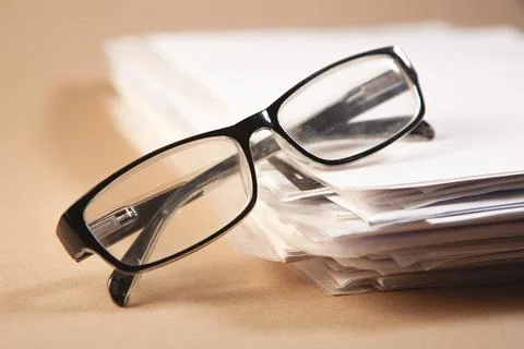 Stack of papers and eyeglasses on a brown background, business concept Stock Photos