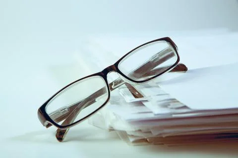 Stack of papers and eyeglasses on white background, business concept Stock Photos