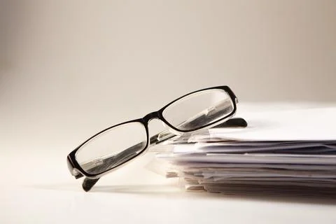 Stack of papers and glasses on a white background. Selective focus. Stock Photos