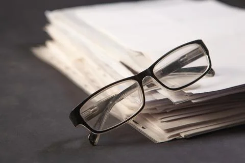 Stack of papers with glasses on the table. Selective focus. Stock Photos