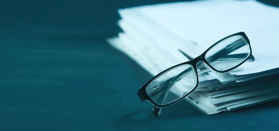 Stack of papers with glasses on the table. Selective focus. Stock Photos
