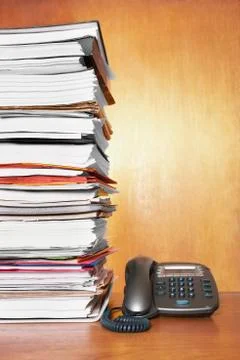Stack of paperwork and telephone on desk Stock Photos