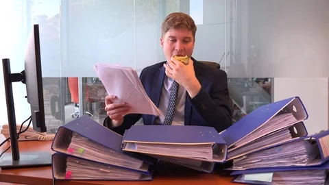 Stack of paperwork on office desk relaxed business man employee eating lunch 4k Stock Footage 82314828