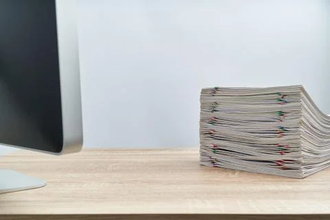 Stack of paperwork overload report and computer on wooden table Stock Photos