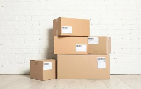 Stack of parcel boxes on floor against brick wall Stock Photos