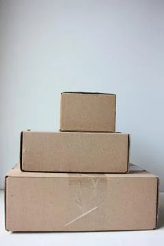 Stack of parcels in brown cardboard boxes on white background. Stock Photos